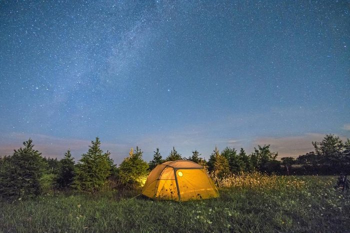 Illuminated camping tent under starry sky