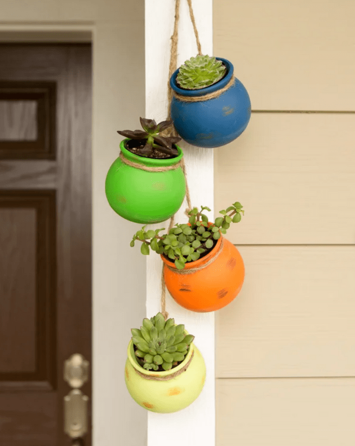 Succulents hang in four colorful, small pots.