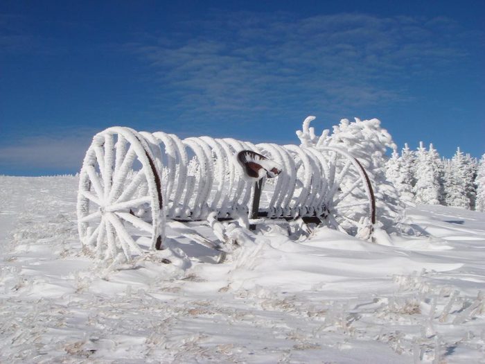 A hay rake in a field covered with hoarfrost.