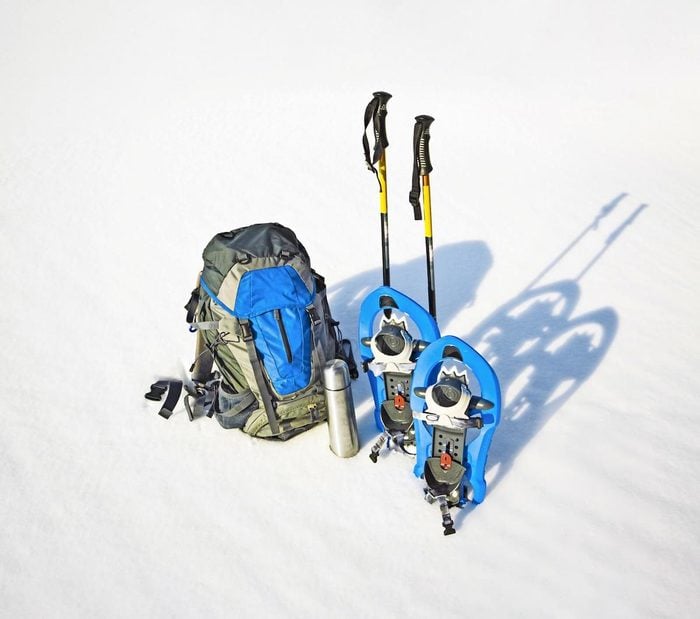 A backpack, showshoes and trekking poles in the snow.