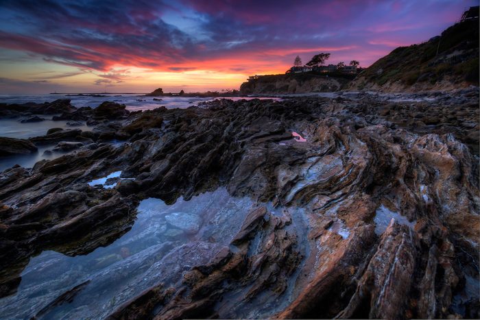 A sunset view of the rocky shoreline at Corona Beach, California
