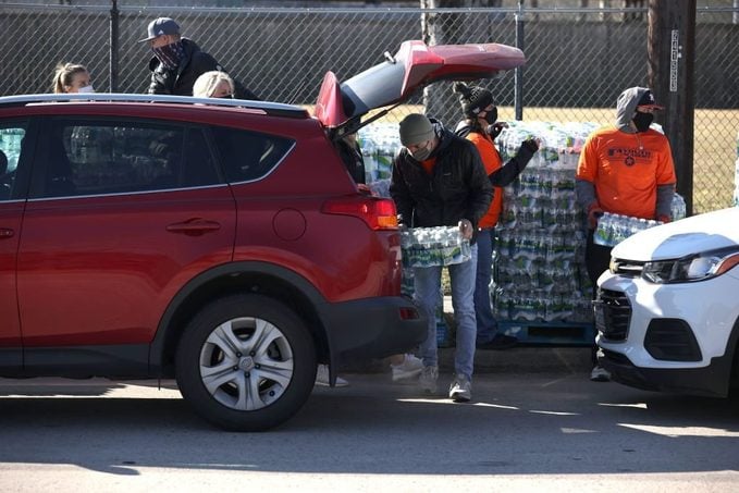 Volunteers load cases of water into a car during a water distribution at the Astros Youth Academy on February 20, 2021 in Houston, Texas.