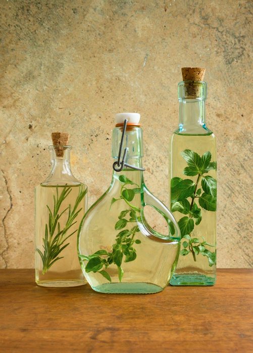 Olive oil bottles with mint, rosemary and oregano leaves
