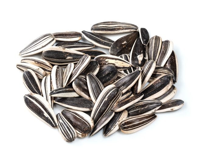 handful of whole sunflower seeds closeup on white