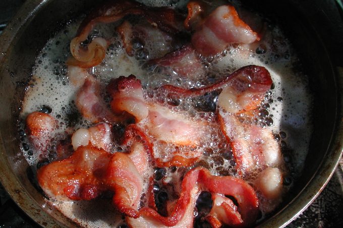 bacon cooking in fat in a skillet