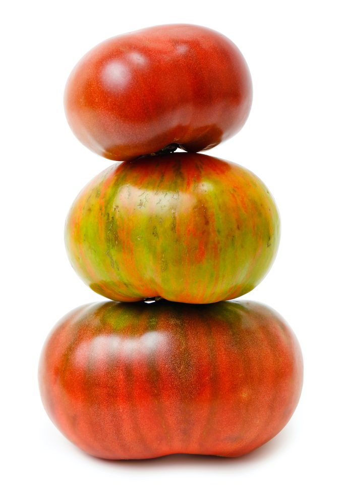 Heirloom tomatoes stack on white background.