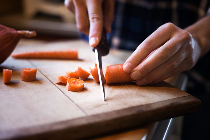 carrot facts, Close-up of woman chopping carrot on cutting board