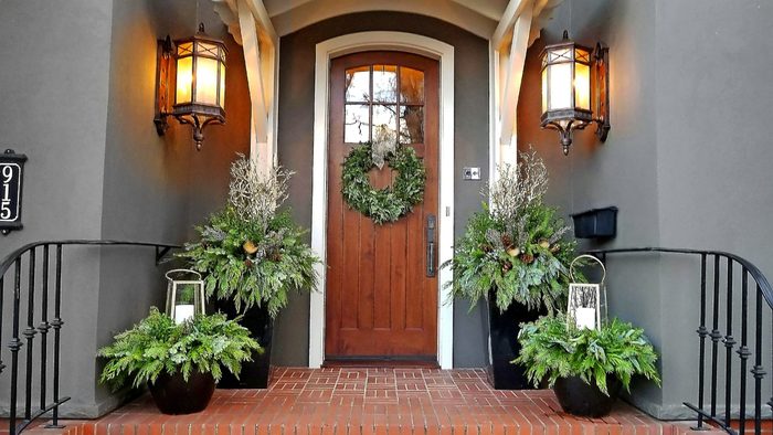 A grouping of winter containers and a wreath decorate a front entryway.