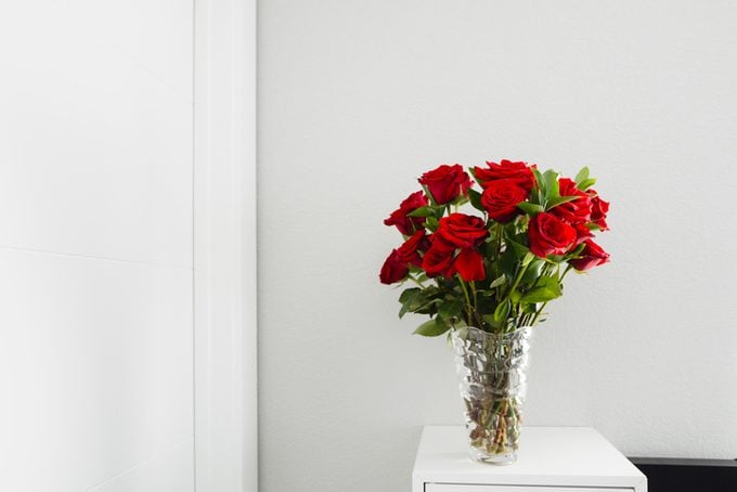 Close-up of roses in vase on table by wall at home